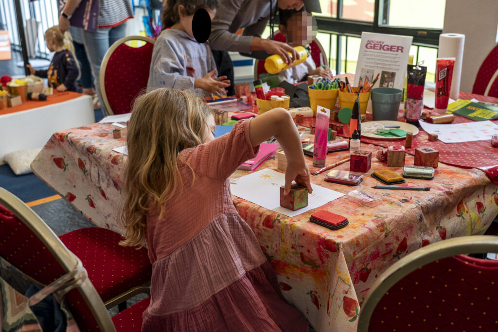 Drei Kinder an einem Tisch stellen Stempel aus Holzklötzen und Moosgummi her.