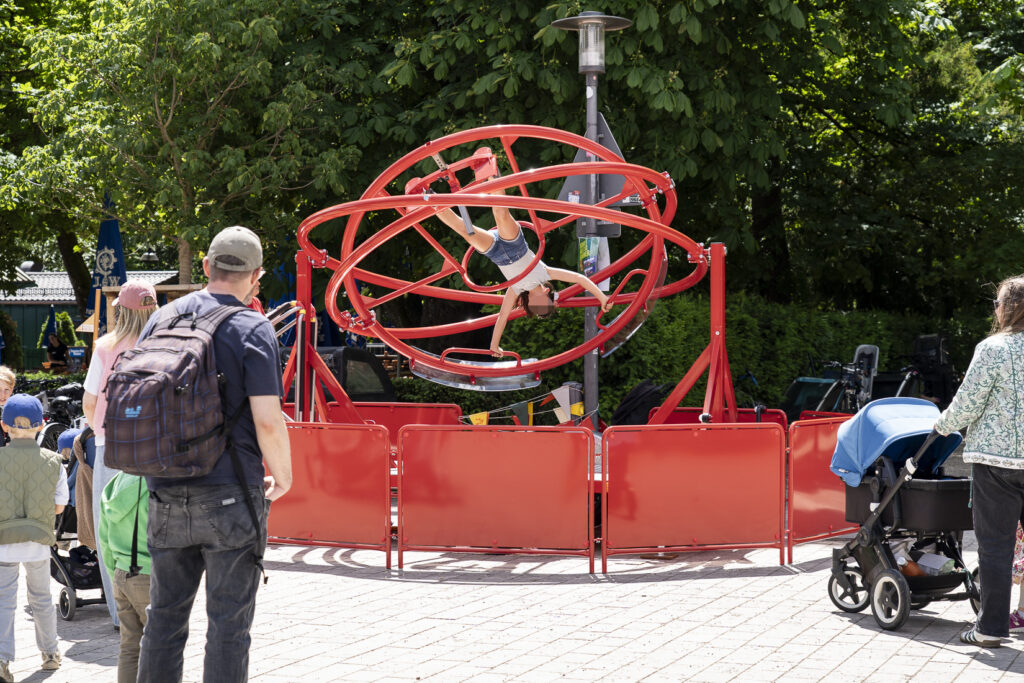 Ein 3D-Flieger in der Mitte des Bildes. Ein Jugendlicher ist dort eingespannt und kann mit seiner Körperbewegung die Richtung bestimmen.