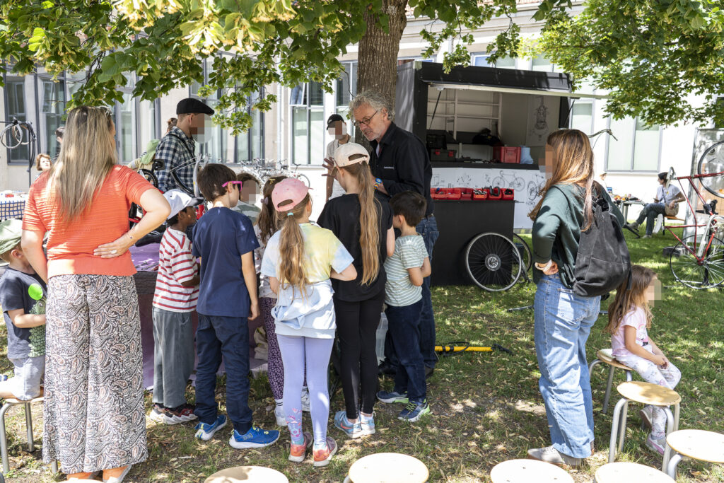 Ein Mann erzählt einer Gruppe von Kinder, wie man Fährräder repariert